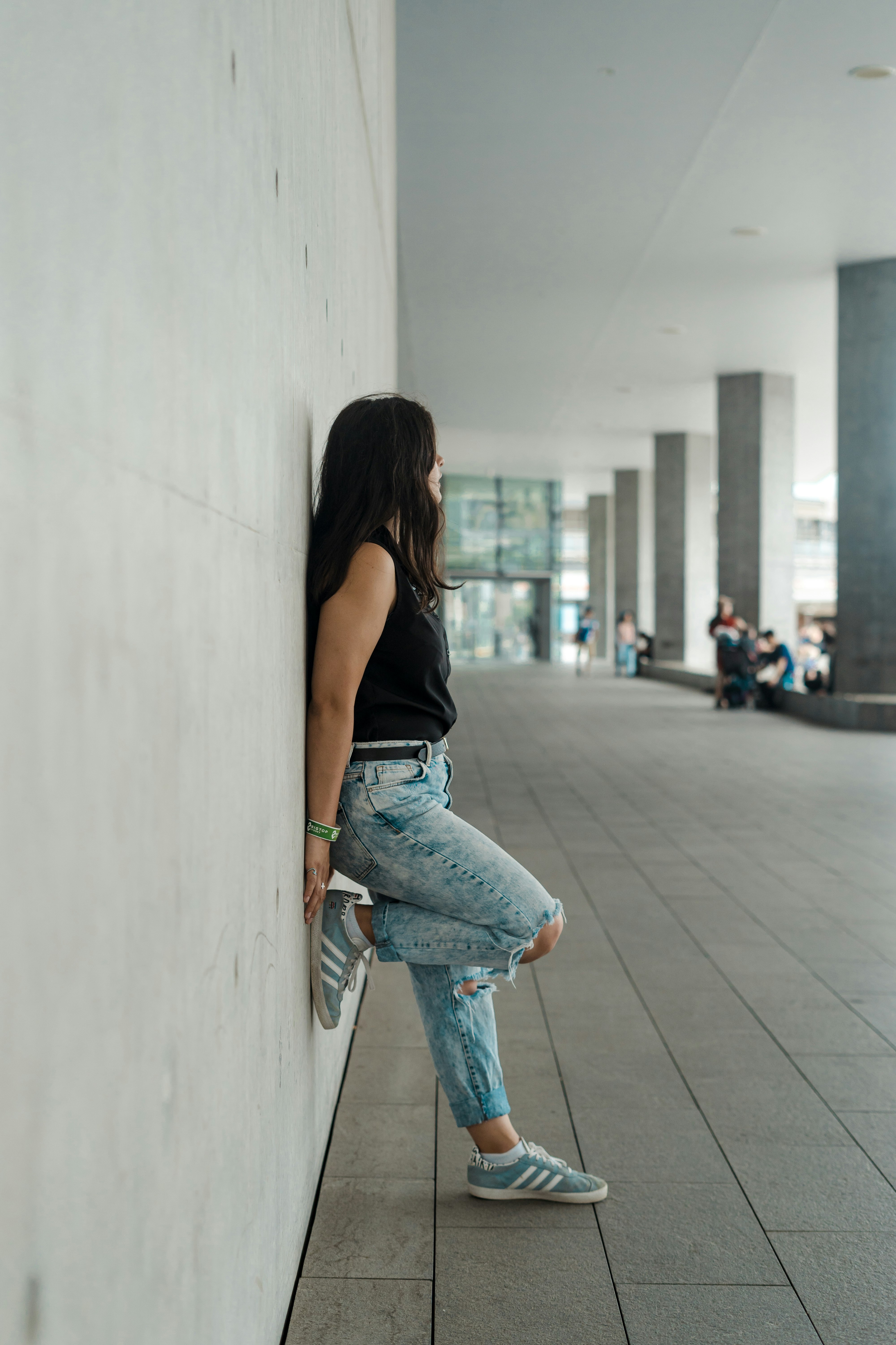 woman in black tank top and blue denim jeans walking on sidewalk during daytime